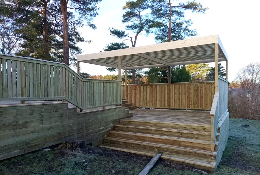 Altan med pergola och trappa ner mot gräsmattan